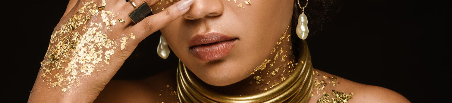 Brunette african american woman with golden accessories and temporary tattoo of gold