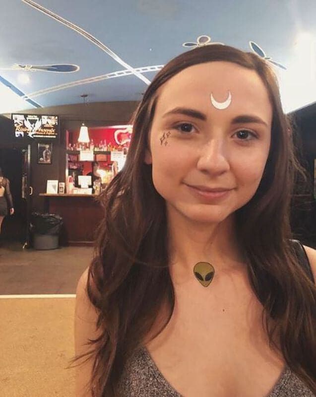 girl wearing a green alien tattoo on collarbone