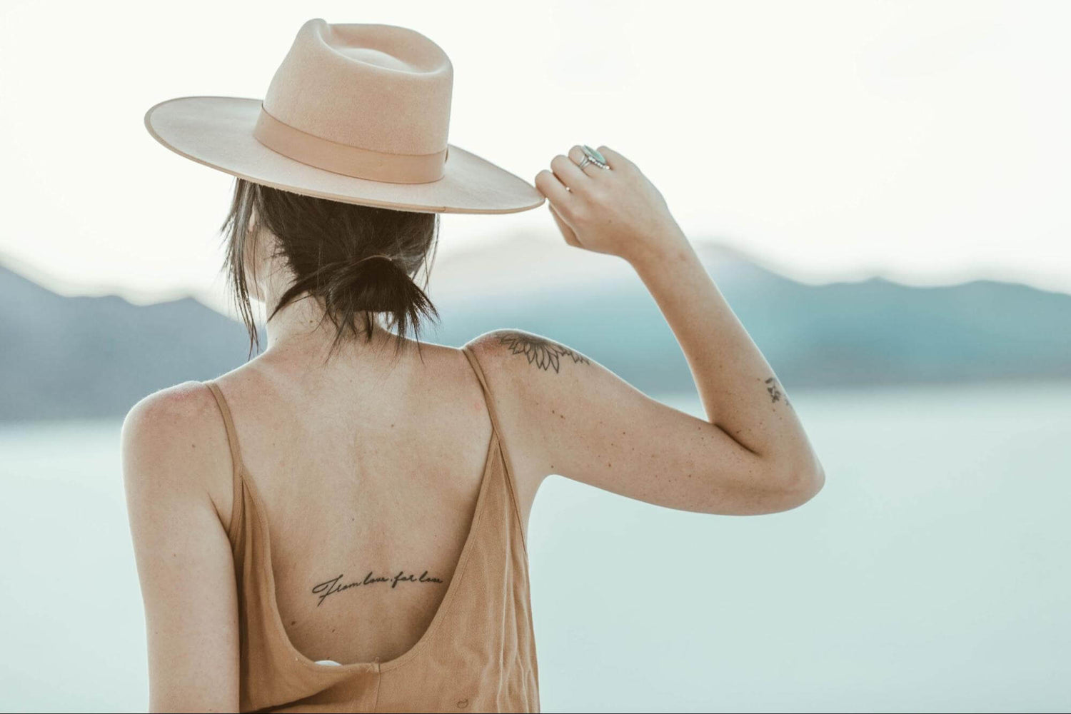 woman by the water with female empowerment tattoos
