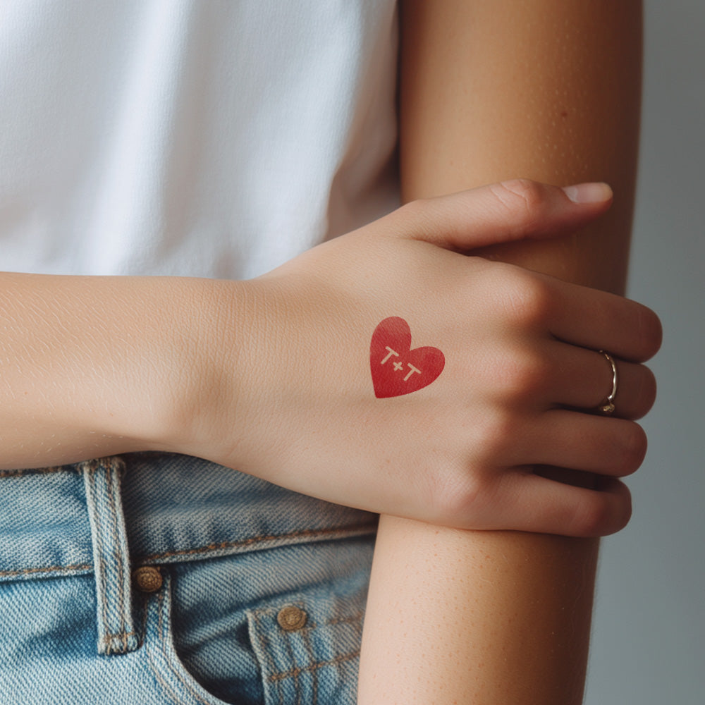 Hand with a red heart-shaped tattoo on a blurred background