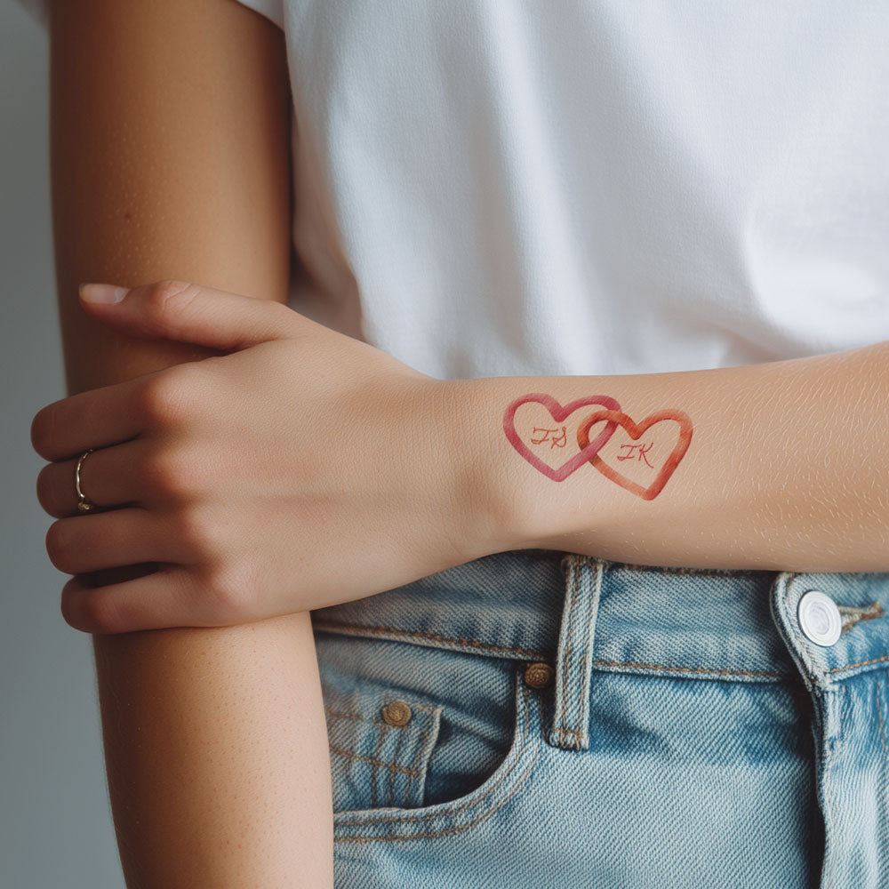 Person wearing a tattoo of two interlocking hearts on their wrist.