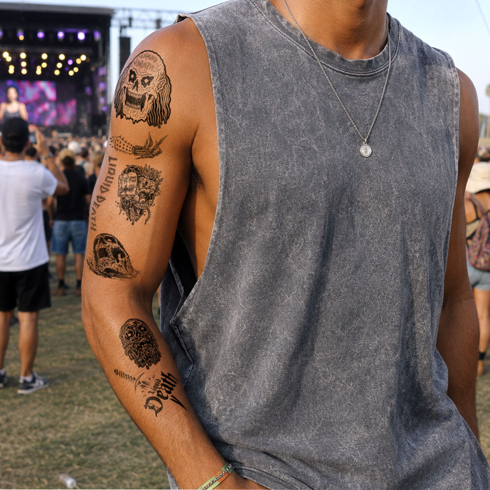 Person with tattoos on arm at a concert with stage and crowd in background