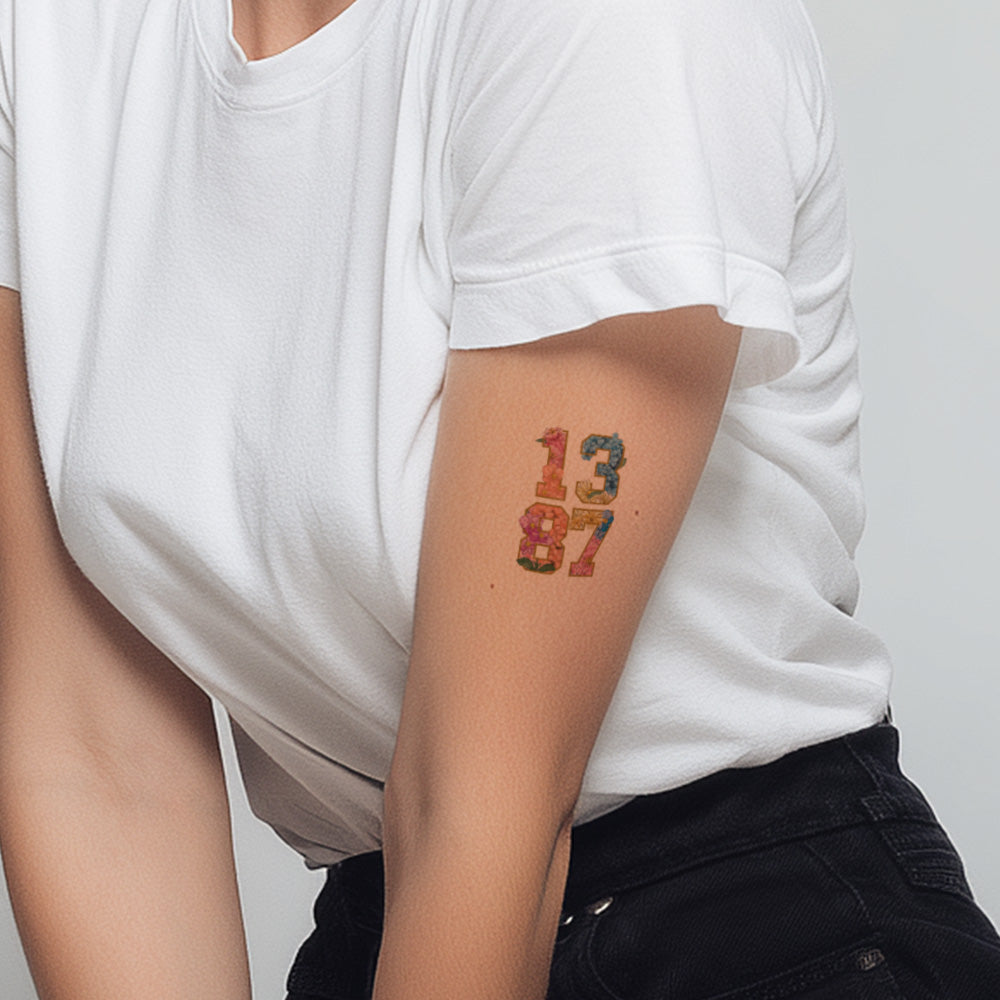 Person wearing a temporary tattoo with colorful numbers on their arm.