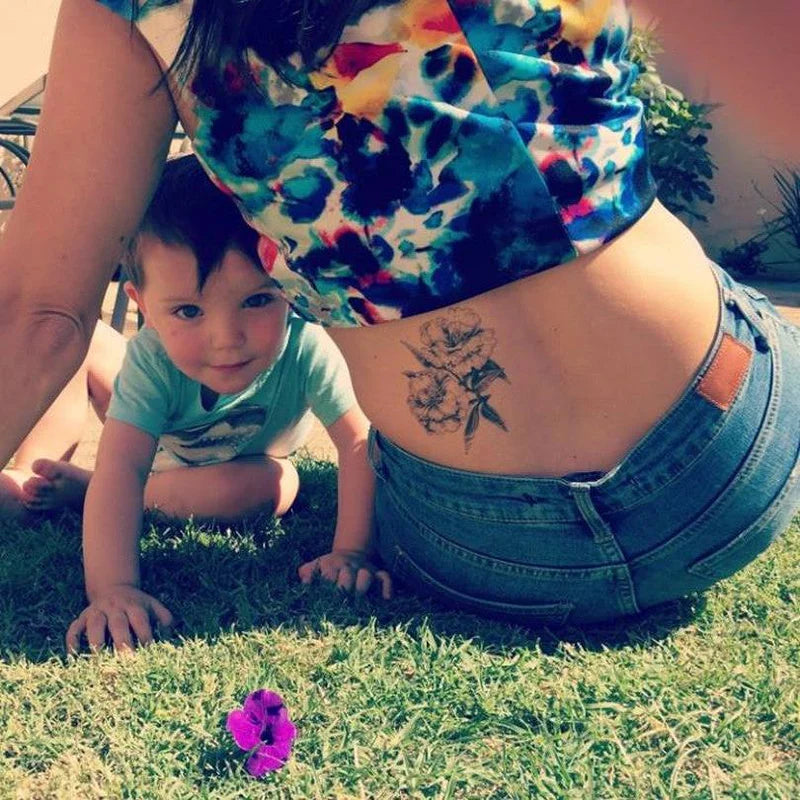 Woman with a tattoo on her back and a child crawling on grass