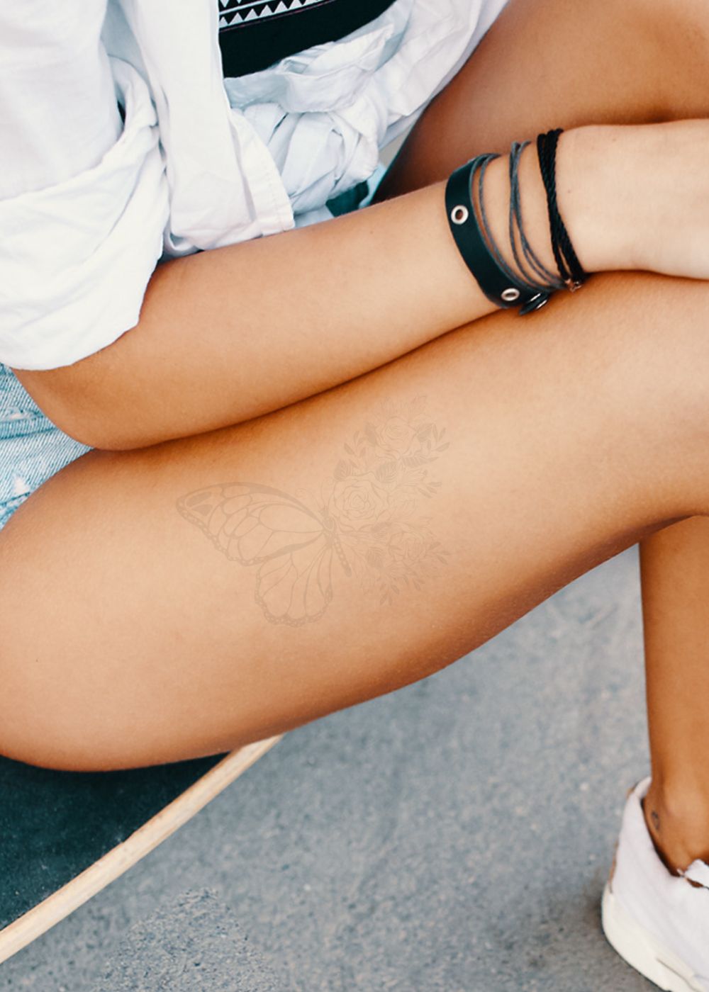 A woman with a faded butterfly tattoo on her thigh.