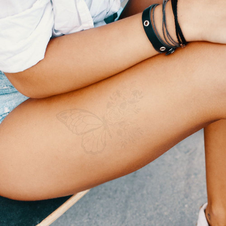 A woman with a faded butterfly tattoo on her thigh.