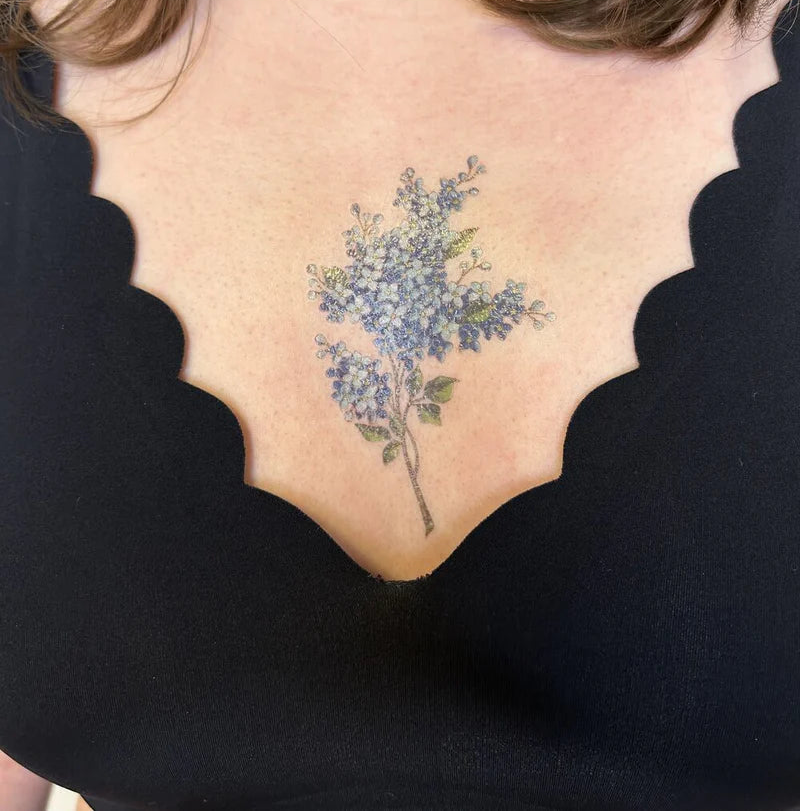 Tattoo of a blue floral design on a person's neck