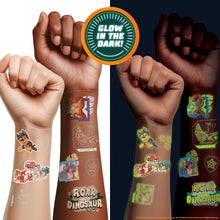 Three human arms and fists are shown wearing temporary tattoo decals, with a circular badge reading 'GLOW IN THE DARK!' at the top. The left arm has light skin with pale outlined tattoos, the middle arm has medium skin tone with slightly darker outlined tattoos, and the right arm is dark-skinned with glowing green/yellow tattoos in the dark.