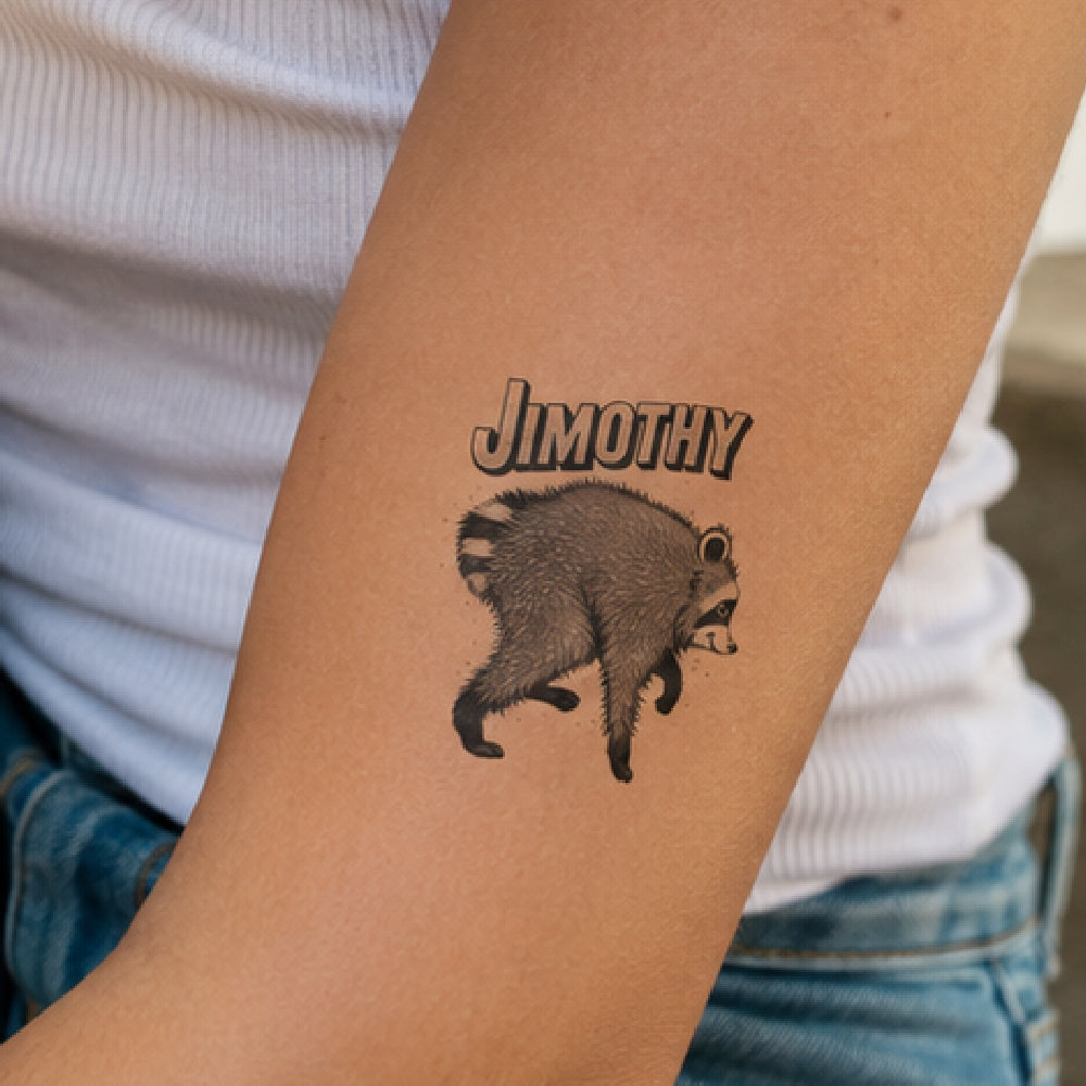 A temporary tattoo on a person's forearm featuring a raccoon and the name 'JIMOTHY' in stylized text, worn over a white ribbed top and blue jeans.