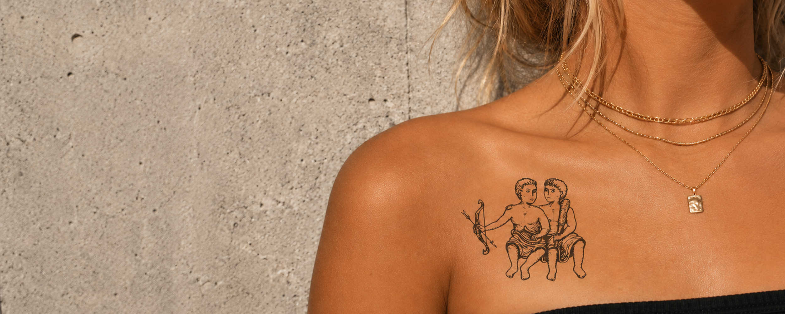 Person with a tattoo of two people on a concrete wall background