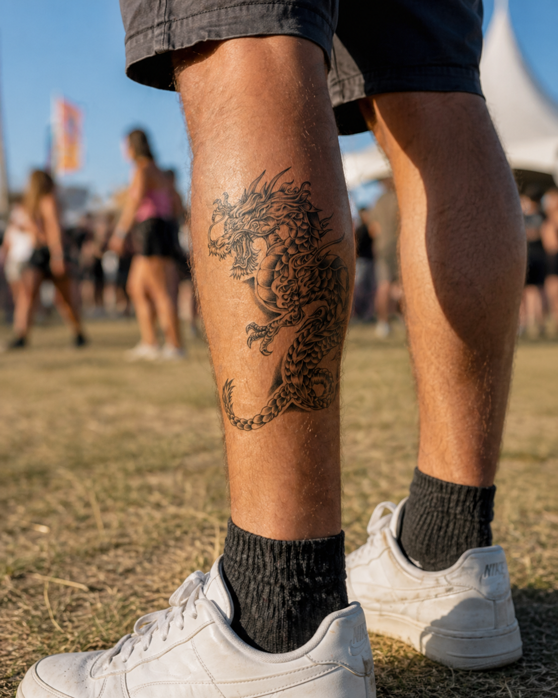 Person wearing white sneakers and black socks with a detailed dragon tattoo on their leg, standing in a grassy outdoor area.