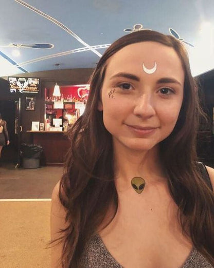 girl wearing a green alien tattoo on collarbone